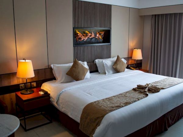 A hotel room featuring a large bed, decorative pillows, bedside lamps, and a modern, cozy atmosphere with a warm color palette.