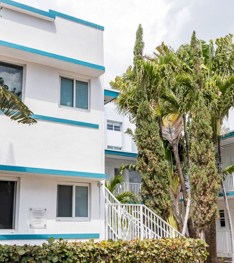 A white building with blue trim and palm trees in front of it
