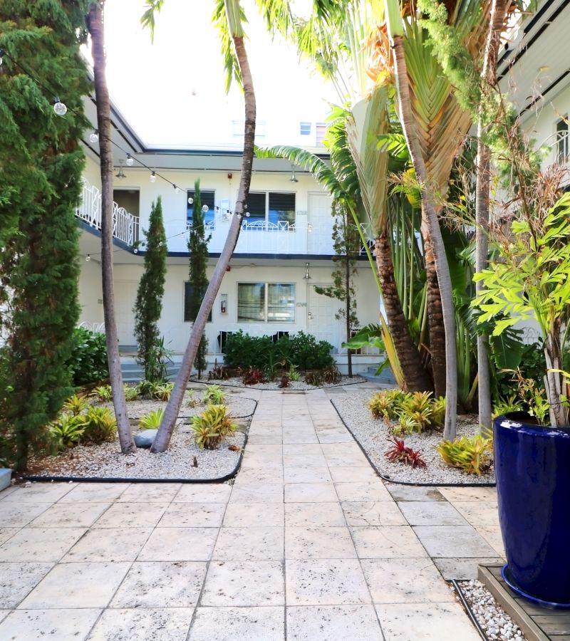 A courtyard with a pathway, plants, and a building in the background.