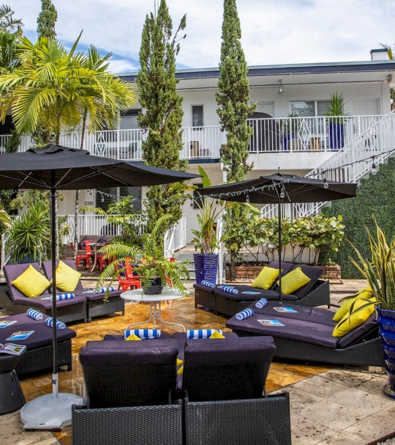 A poolside area with lounge chairs, umbrellas, and plants.